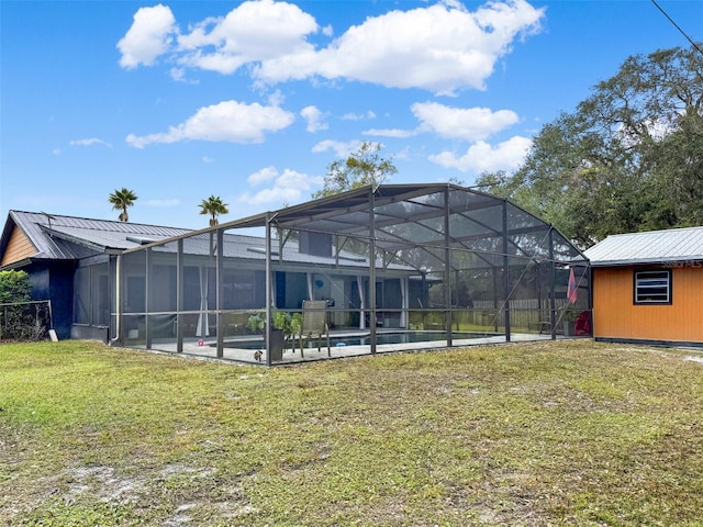 rear view of property with a yard, a patio, metal roof, and an outdoor pool