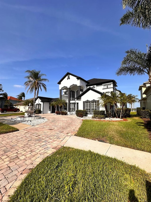 mediterranean / spanish house featuring stucco siding, decorative driveway, and a front lawn