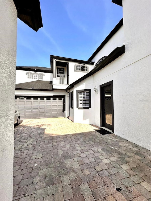 view of patio featuring a balcony, driveway, and an attached garage
