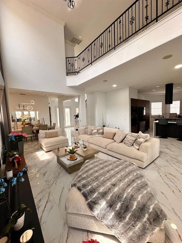 living area with a towering ceiling, visible vents, and marble finish floor