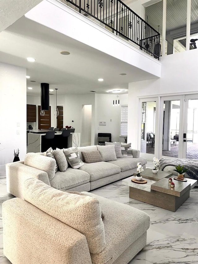 living area with recessed lighting, a towering ceiling, and marble finish floor