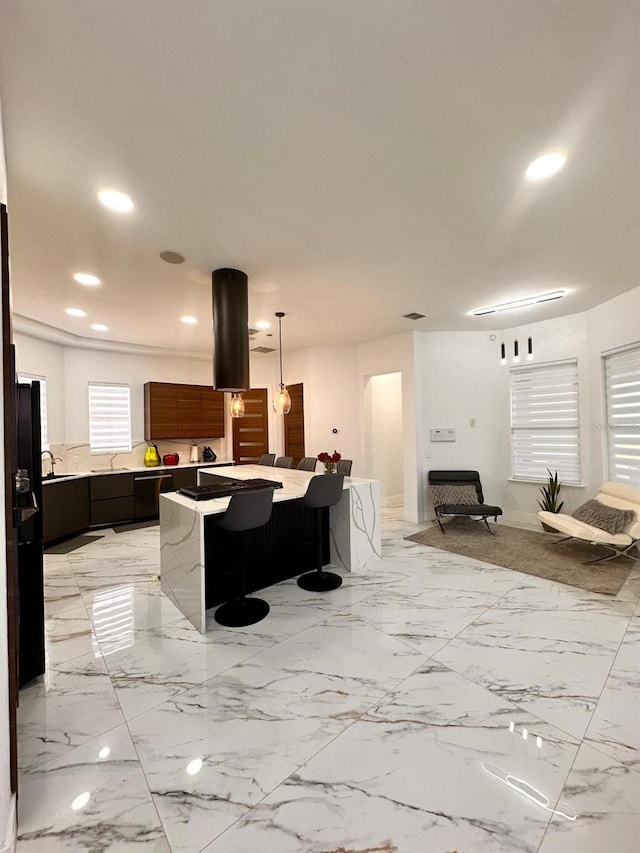 kitchen with a kitchen breakfast bar, a kitchen island, recessed lighting, and a sink