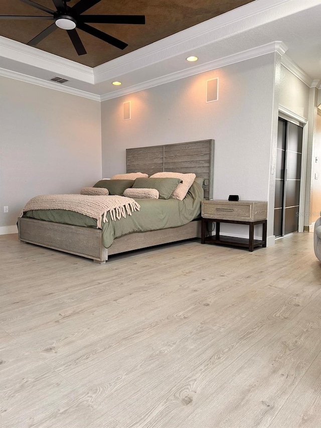bedroom featuring crown molding, a raised ceiling, ceiling fan, visible vents, and wood finished floors
