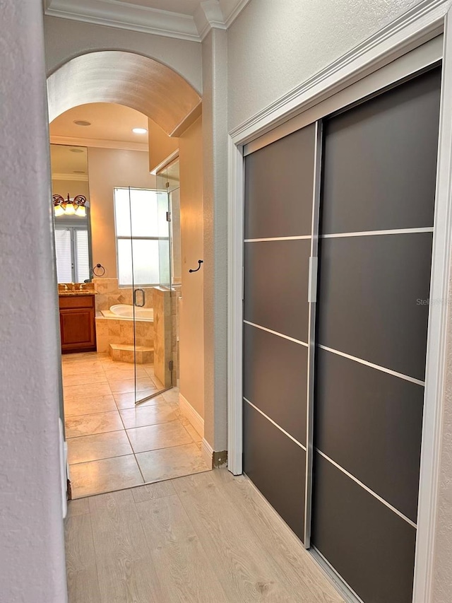 corridor with ornamental molding, arched walkways, and wood finished floors