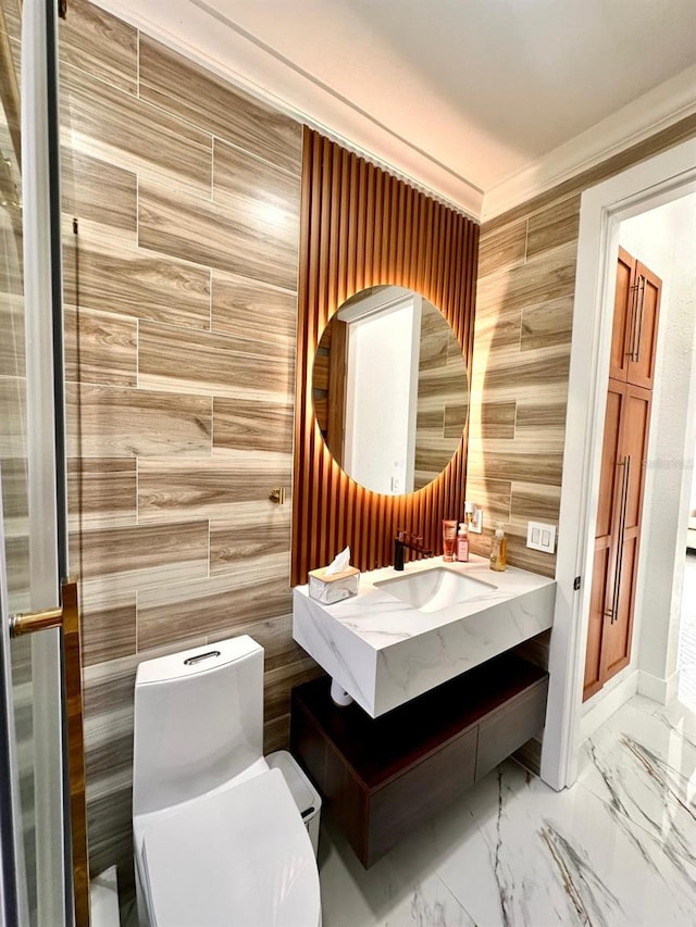 bathroom featuring marble finish floor, toilet, vanity, wooden walls, and crown molding
