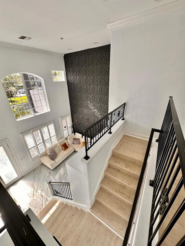 stairs featuring crown molding, visible vents, wood finished floors, and baseboards