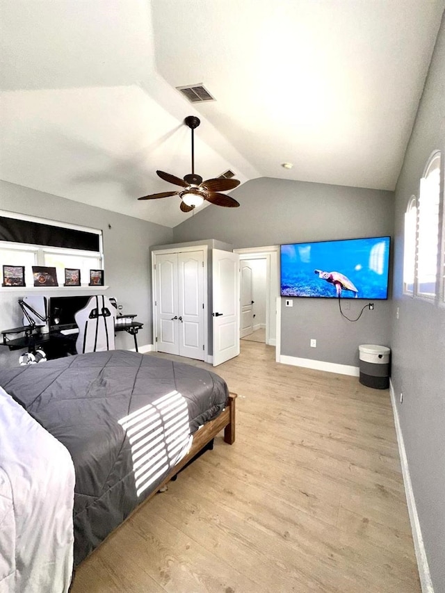 bedroom featuring light wood finished floors, visible vents, vaulted ceiling, and baseboards