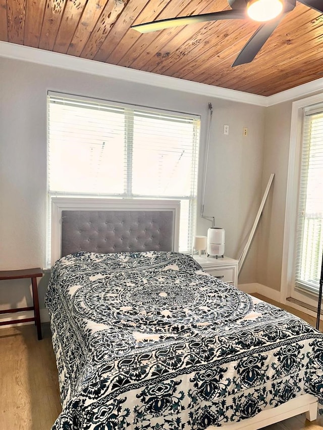 bedroom featuring multiple windows, wood finished floors, ornamental molding, and wooden ceiling