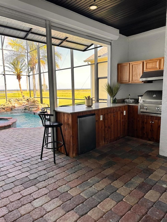 kitchen with refrigerator, brick floor, under cabinet range hood, and a sink