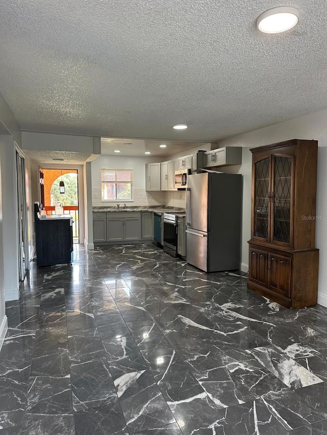 kitchen featuring a textured ceiling, stainless steel appliances, light countertops, and baseboards