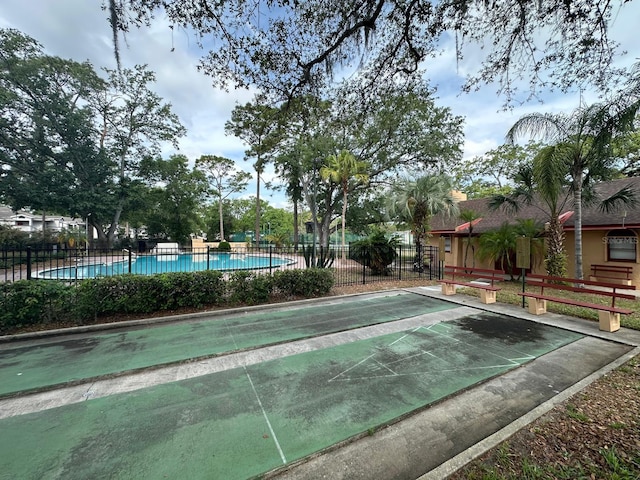 view of community featuring shuffleboard, fence, and a swimming pool