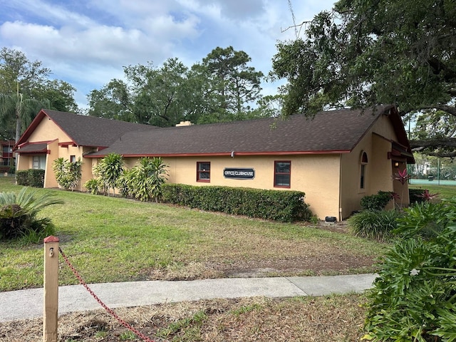 view of front of home featuring a front lawn, stucco siding, and roof with shingles