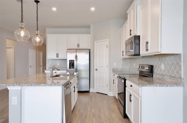 kitchen featuring white cabinetry, a sink, stainless steel appliances, light wood-style flooring, and an island with sink