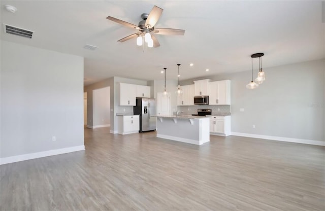 unfurnished living room featuring baseboards, visible vents, ceiling fan, and wood finished floors