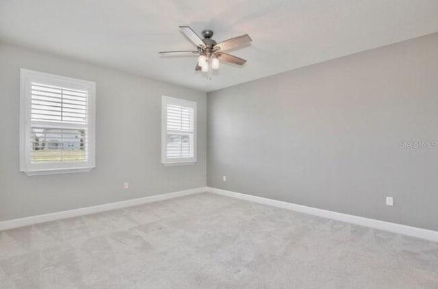 carpeted spare room with ceiling fan and baseboards