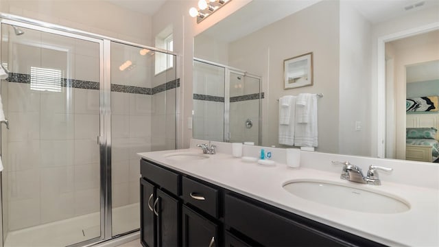 ensuite bathroom featuring visible vents, a stall shower, double vanity, and a sink