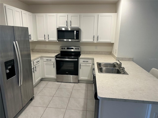 kitchen with white cabinets, a sink, stainless steel appliances, light countertops, and a peninsula