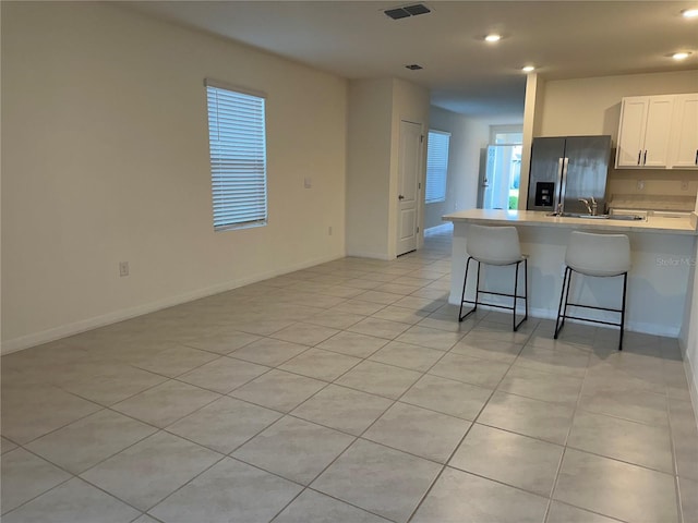 kitchen with recessed lighting, a kitchen breakfast bar, stainless steel fridge with ice dispenser, and light countertops