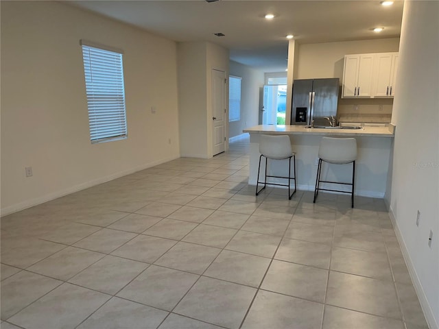 kitchen featuring recessed lighting, a kitchen breakfast bar, stainless steel refrigerator with ice dispenser, a peninsula, and white cabinetry