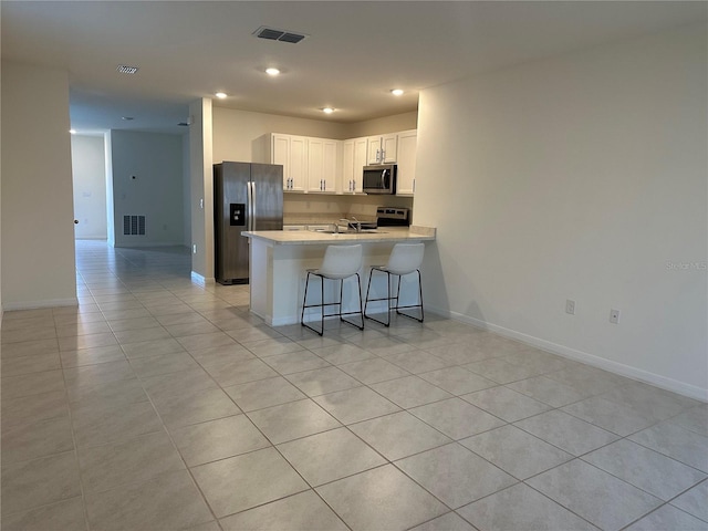 kitchen with white cabinetry, visible vents, stainless steel appliances, light countertops, and a peninsula