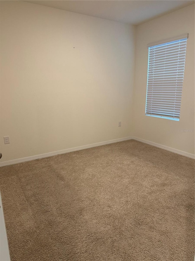 carpeted spare room featuring baseboards