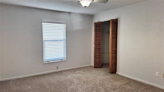 unfurnished bedroom with a closet, light carpet, baseboards, and ceiling fan