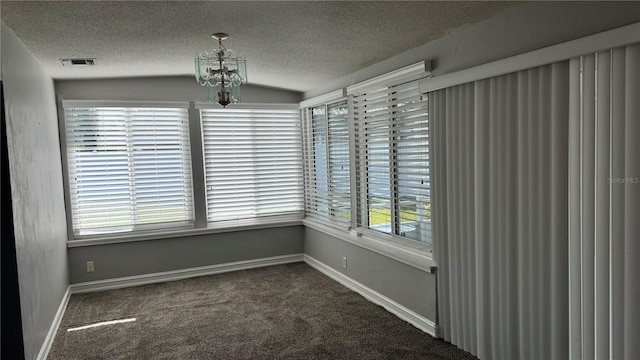 unfurnished dining area with a textured ceiling, plenty of natural light, carpet, and visible vents