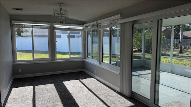 unfurnished sunroom featuring carpet flooring, a notable chandelier, visible vents, baseboards, and vaulted ceiling