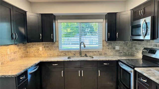 kitchen featuring a sink, dark cabinetry, backsplash, and appliances with stainless steel finishes
