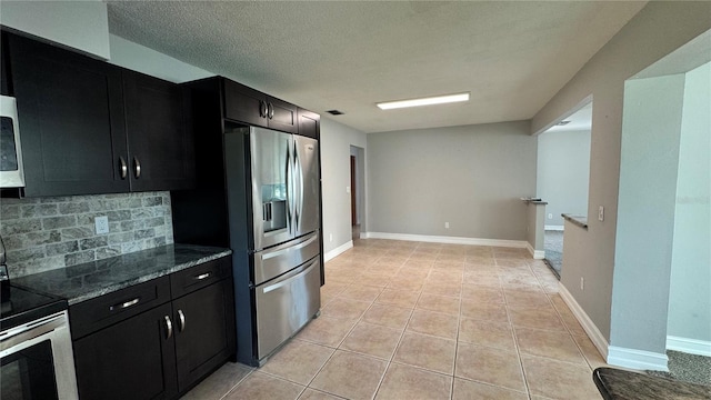 kitchen with dark cabinetry, decorative backsplash, light tile patterned floors, and appliances with stainless steel finishes