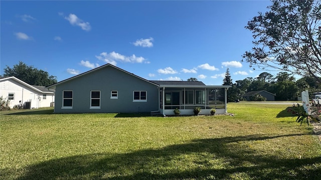 rear view of house featuring a sunroom, a yard, stucco siding, and central AC unit
