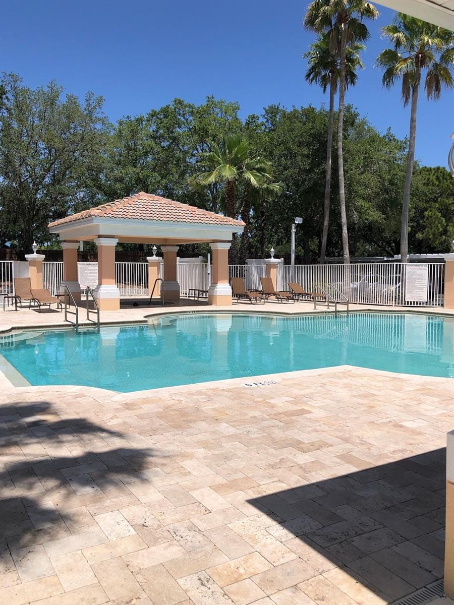 community pool with fence, a patio area, and a gazebo