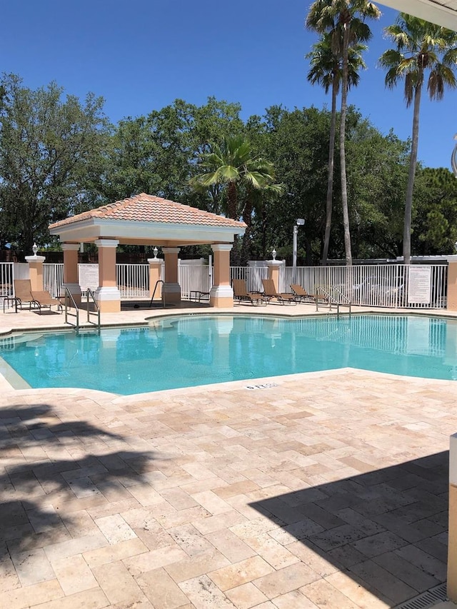community pool with fence, a patio area, and a gazebo