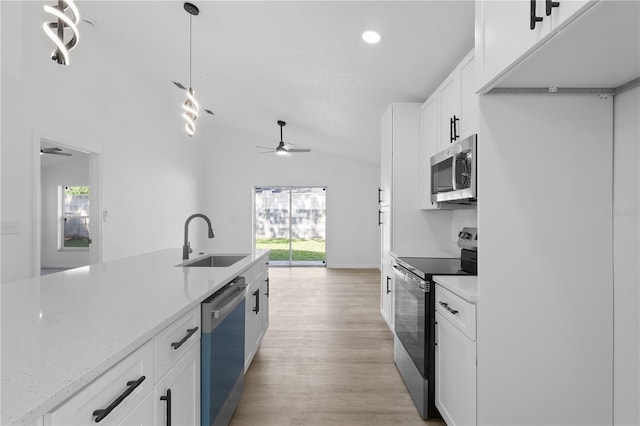 kitchen featuring appliances with stainless steel finishes, vaulted ceiling, ceiling fan, a sink, and white cabinetry