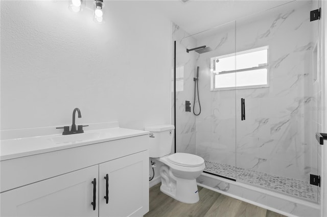 bathroom with wood finished floors, a marble finish shower, toilet, and vanity