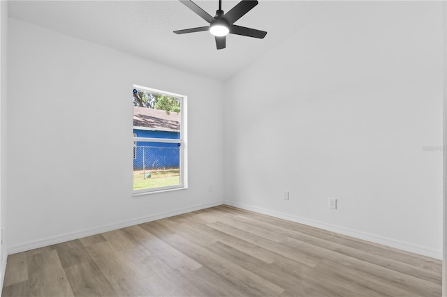 empty room featuring a ceiling fan, baseboards, vaulted ceiling, and light wood-style floors