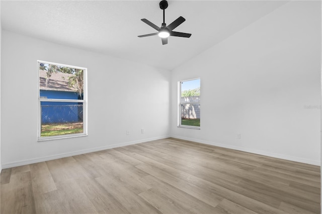 spare room with light wood finished floors, a ceiling fan, lofted ceiling, and plenty of natural light