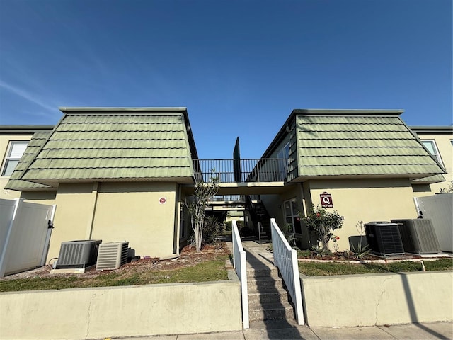 1799 N Highland Ave Unit 143, Clearwater, FL 33755 - view of front of property featuring stucco siding, fence private yard, mansard roof, central AC, and a balcony