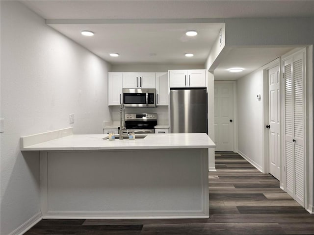 1799 N Highland Ave Unit 143, Clearwater, FL 33755 - kitchen with dark wood finished floors, white cabinetry, appliances with stainless steel finishes, baseboards, and a peninsula