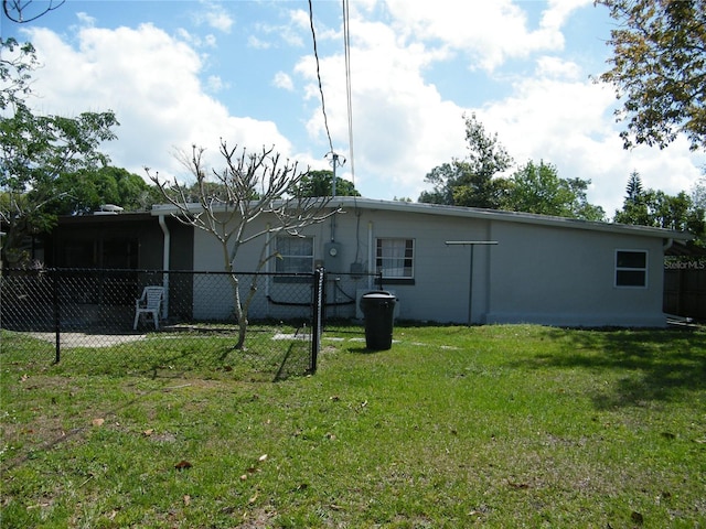 rear view of property with fence and a lawn