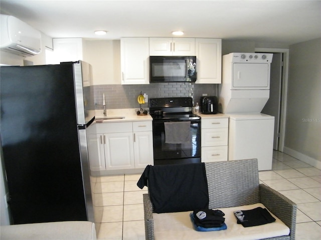 kitchen featuring a sink, stacked washing maching and dryer, a wall mounted air conditioner, light tile patterned flooring, and black appliances