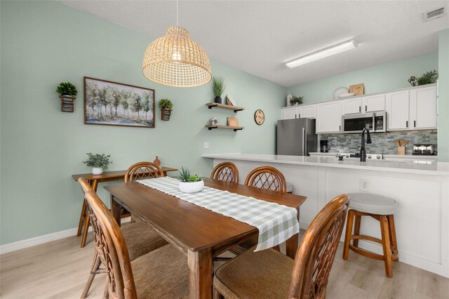 4722 Flagler Beach Way, Kissimmee, FL 34746 - dining room featuring baseboards, visible vents, light wood-style floors, and a textured ceiling