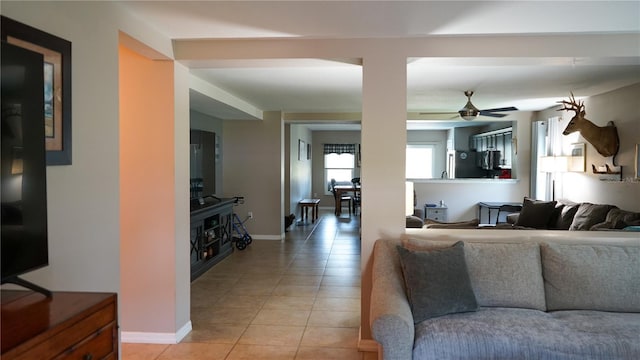 living room featuring light tile patterned floors, baseboards, and ceiling fan