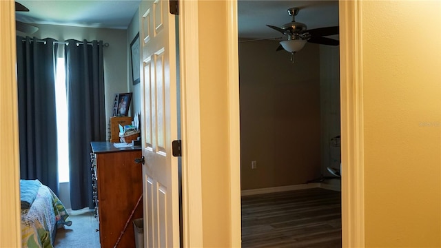 corridor with baseboards, wood finished floors, and a healthy amount of sunlight