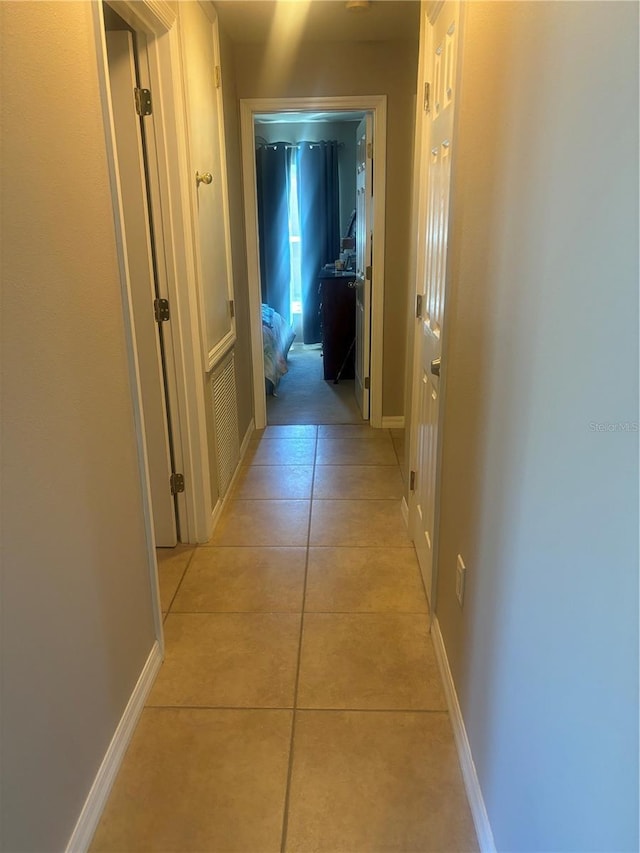 hallway featuring baseboards and light tile patterned floors