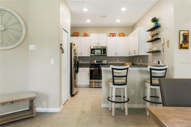 13475 Crest Lake Dr, Hudson, FL 34669 - kitchen featuring a kitchen breakfast bar, white cabinetry, open shelves, stainless steel appliances, and a peninsula