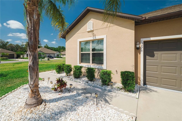 13475 Crest Lake Dr, Hudson, FL 34669 - view of side of property with a lawn, a garage, and stucco siding