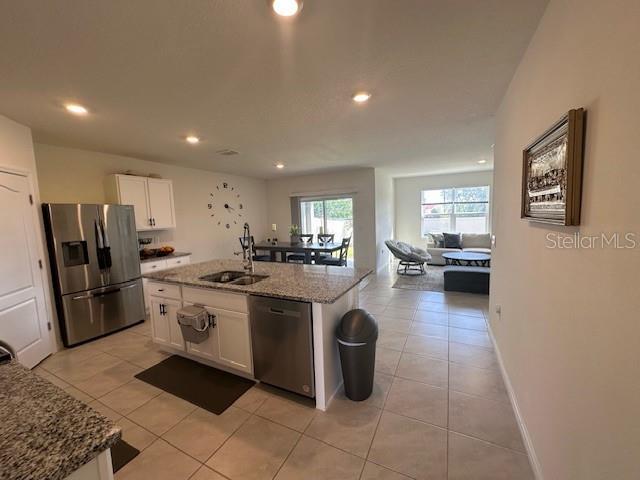 4373 Deleon St, Haines City, FL 33844 - kitchen with light stone countertops, appliances with stainless steel finishes, a sink, white cabinetry, and light tile patterned floors