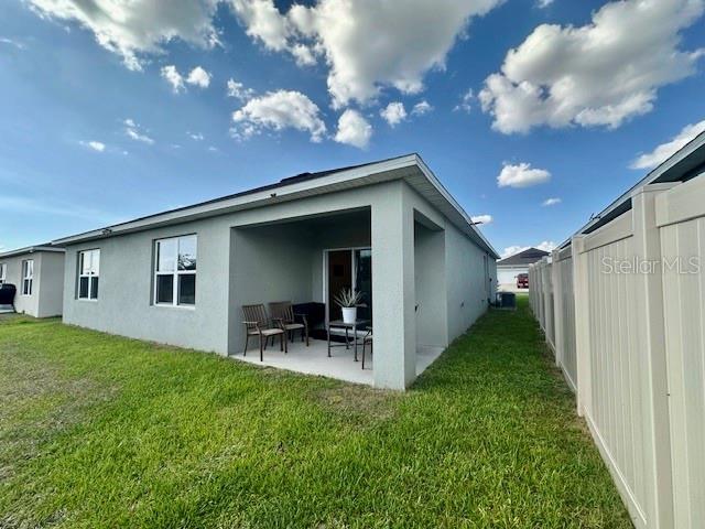 4373 Deleon St, Haines City, FL 33844 - rear view of property with fence, stucco siding, a yard, and a patio area
