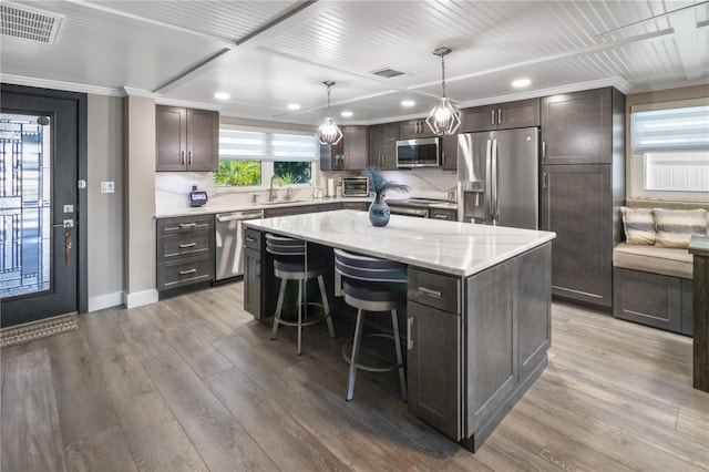 kitchen featuring a center island, dark brown cabinets, crown molding, light wood-style floors, and appliances with stainless steel finishes
